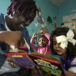 A woman reads a book to two small children.