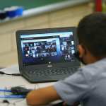 Justin Castilla works on a laptop in a classroom in Newlon Elementary School early Tuesday, Aug. 25, 2020, which is one of 55 Discovery Link sites set up by Denver Public Schools where students are participating in remote learning in this time of the new coronavirus from a school in Denver.