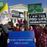 A group of protesters standing outside of the Supreme Court holding anti-abortion signs.