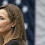 Amy Coney Barrett stands in front of the American flag.