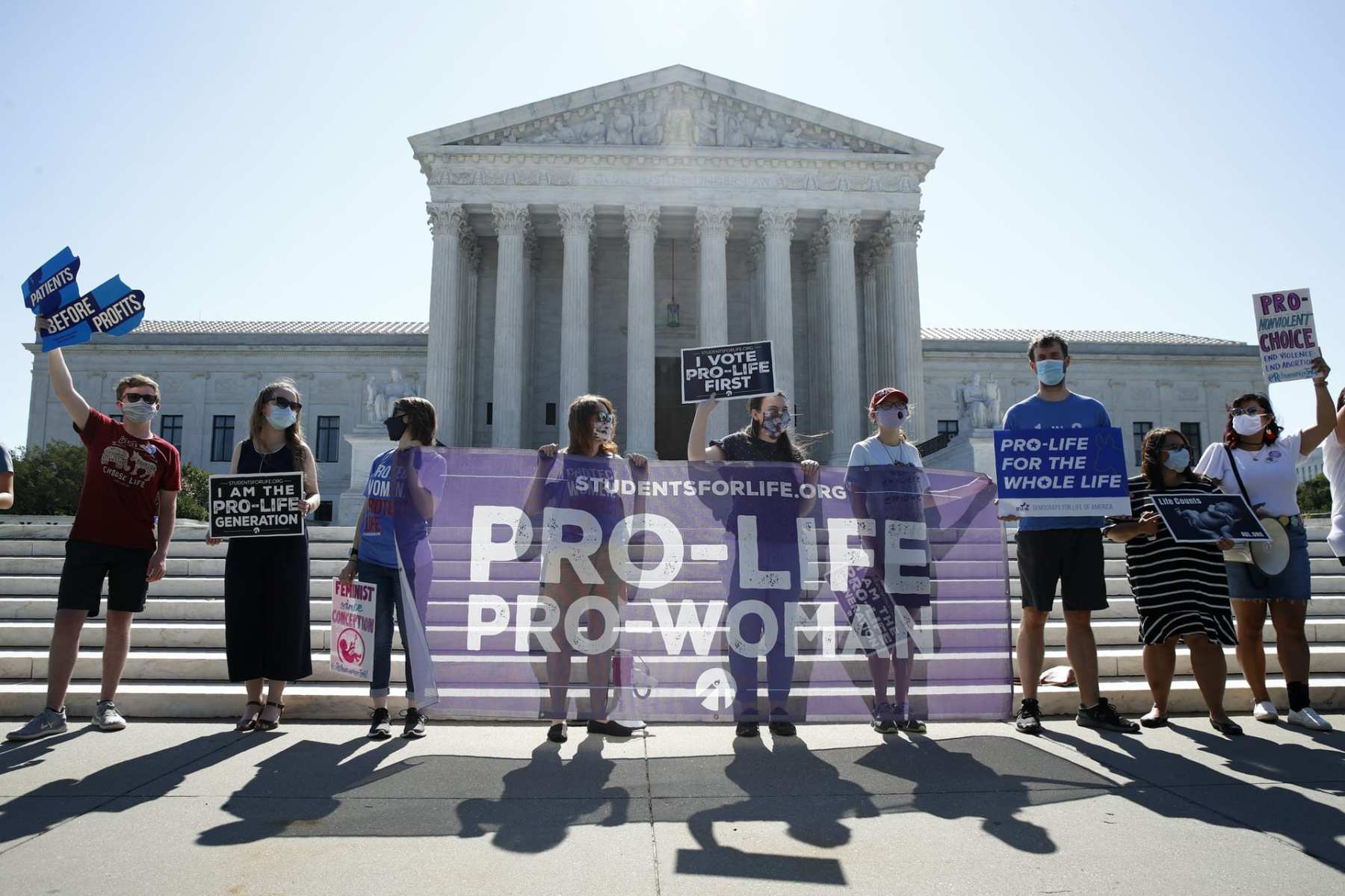 A group stands in front of the Supreme Court with a sign that reads, "pro life, pro-woman."