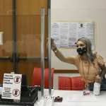 A poll worker cleans a plexiglass barrier at a Texas polling place.