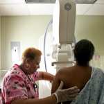 A woman administers a mammogram to another woman.