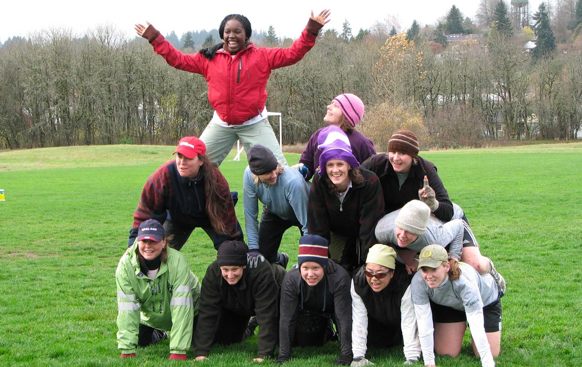 A group posing in a pyramid on a football field.