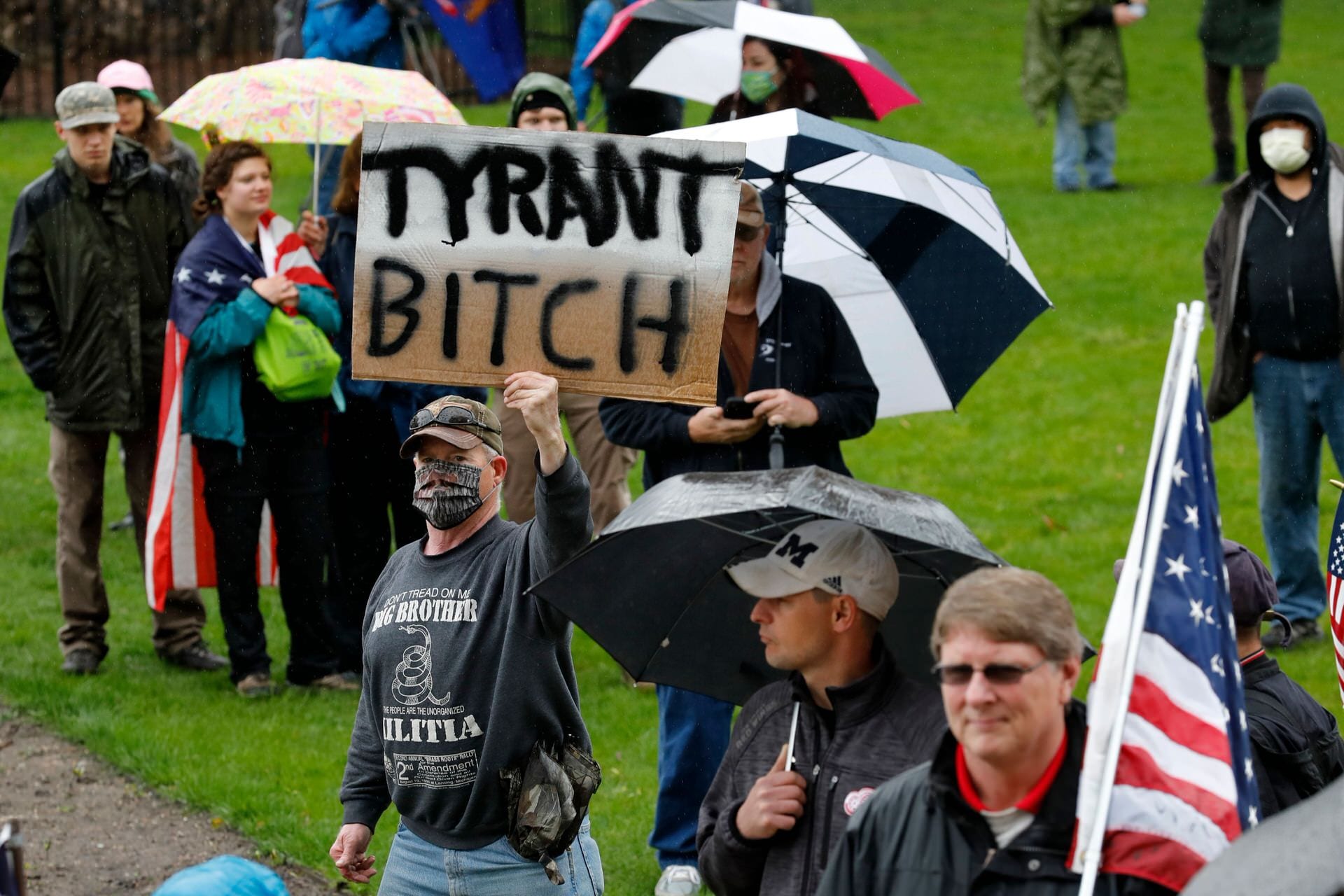 A man holds a sign with "tyrant bitch" written on it.
