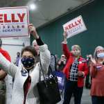 Supporters of Kelly Loeffler hold signs at a rally.