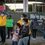 A woman stands with her two kids at a protest.