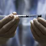 A medical professional holding a dose of a vaccine.