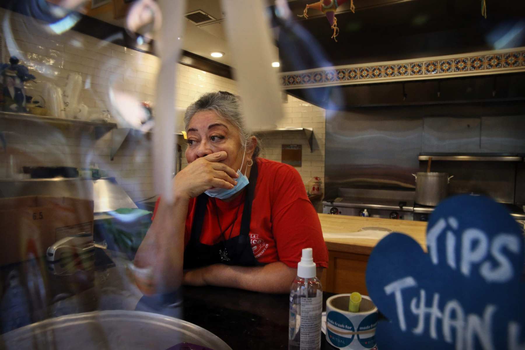 Owner Julie King, in a red shirt covered by an apron, holds back tears at Villa Mexico Cafe on Water Street in Boston, MA. A customer had just walked out while she was on the phone with another customer who was trying to negotiate the price of an order. Having lost two customers in a matter of minutes she said, "I'm going to cry." The pandemic crushed businesses on Boston's Water Street. Even more devastating: The effects ripple around the world.