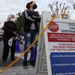 eople wait outside a COVID-19 vaccine distribution center.