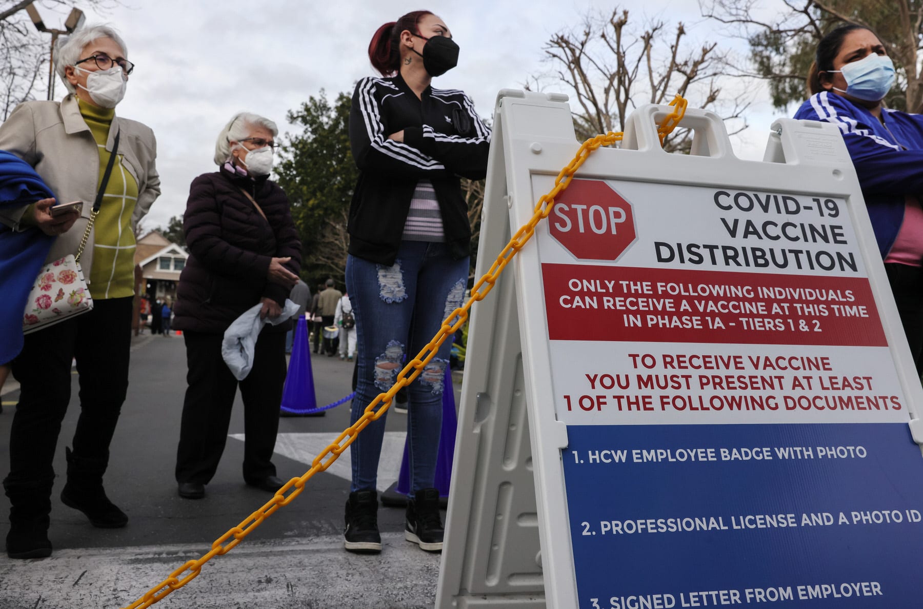 eople wait outside a COVID-19 vaccine distribution center.