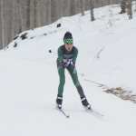 A girl skiing in a snowy forest.