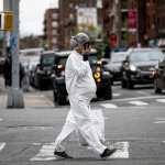 pregnant woman wearing a hazmat suit and a mask walks in the streets in the Elmhurst neighbourhood.