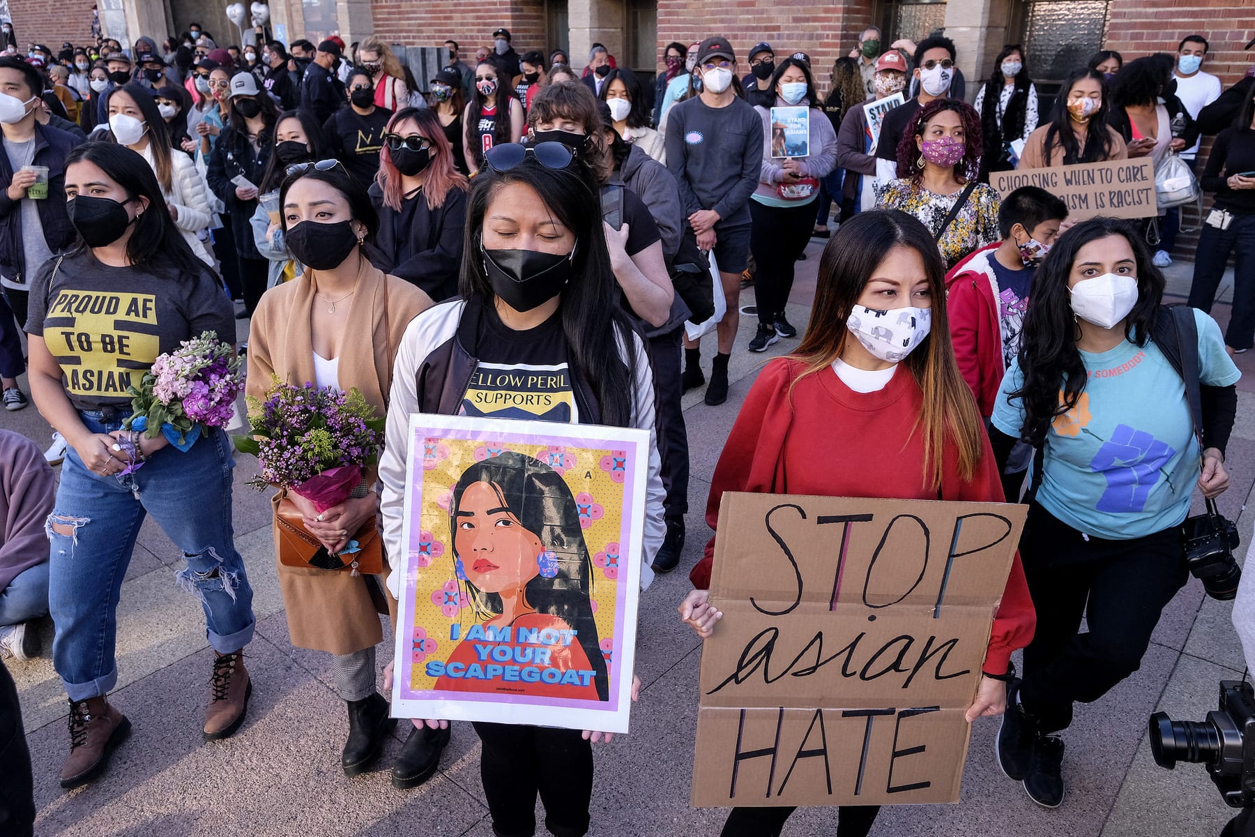 Demonstrators wearing face masks and holding signs take part in a rally
