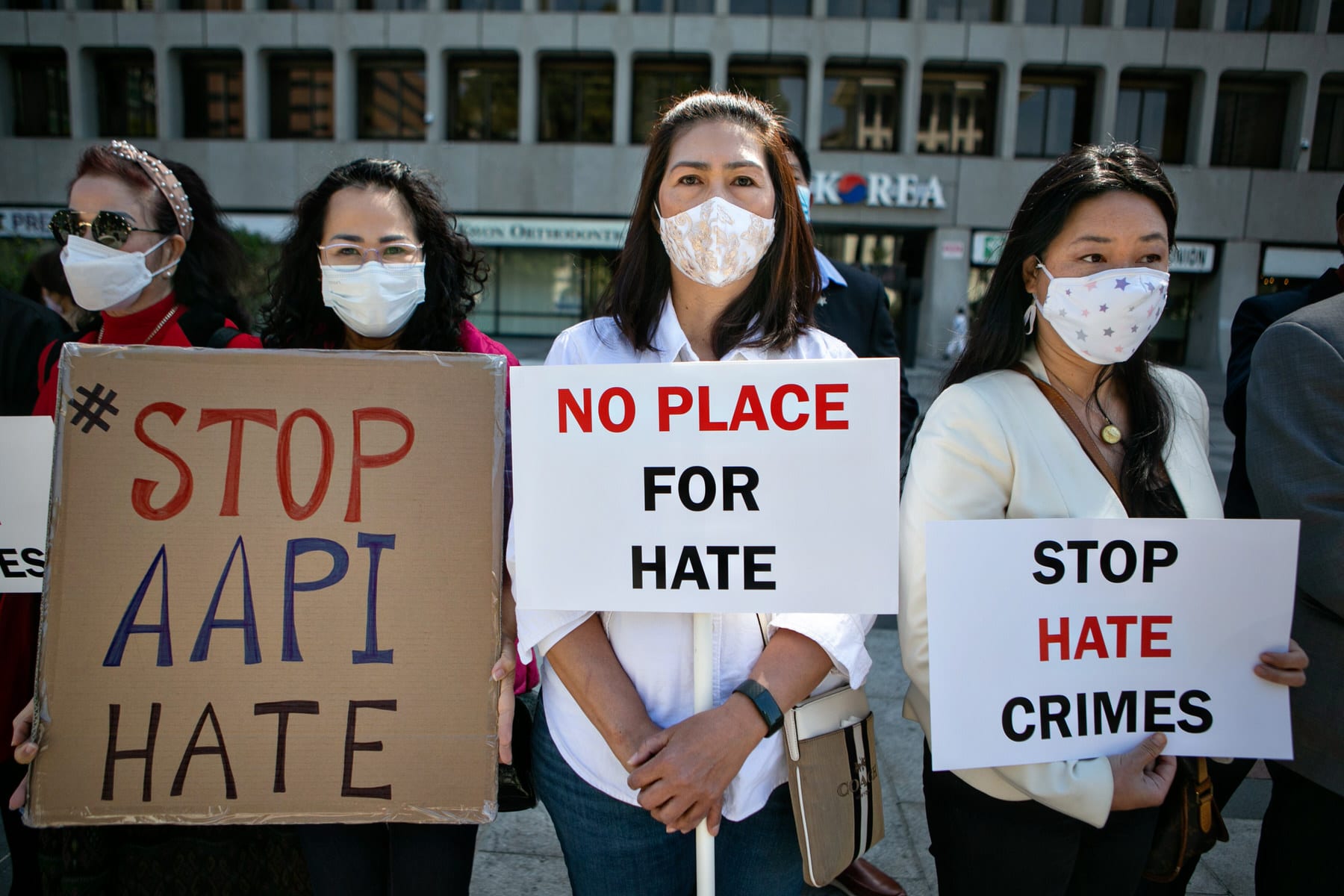 Asian community members hold signs calling for hate to stop.