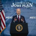 Joe Biden speaking at a podium in front of a backdrop that reads 