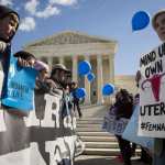 Protesters with both anti-abortion and abortion rights signs stand in front of the Supreme Court.