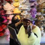 Woman helping another woman try on hats