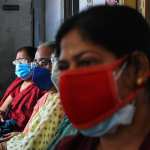 Women are wearing protective masks and waiting outside a covid-19 vaccination center.