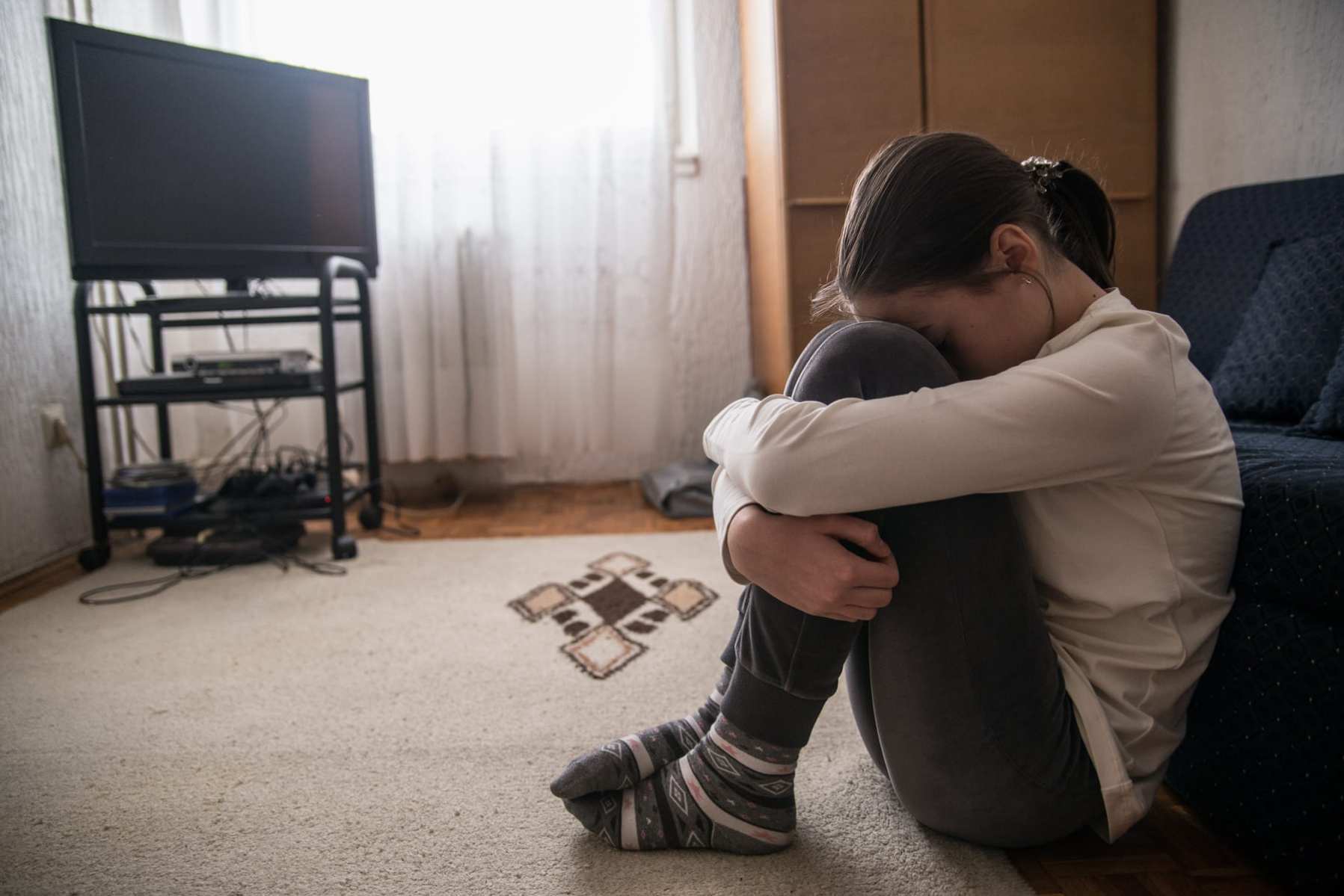 Teen woman with headache holding her head in her living room during the day