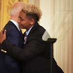 Ashton Mota embraces Biden with an American flag beside them