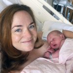 A mother holds her newborn in a hospital bed.