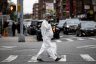 A pregnant woman wearing a hazmat suit and a mask walks in the streets.