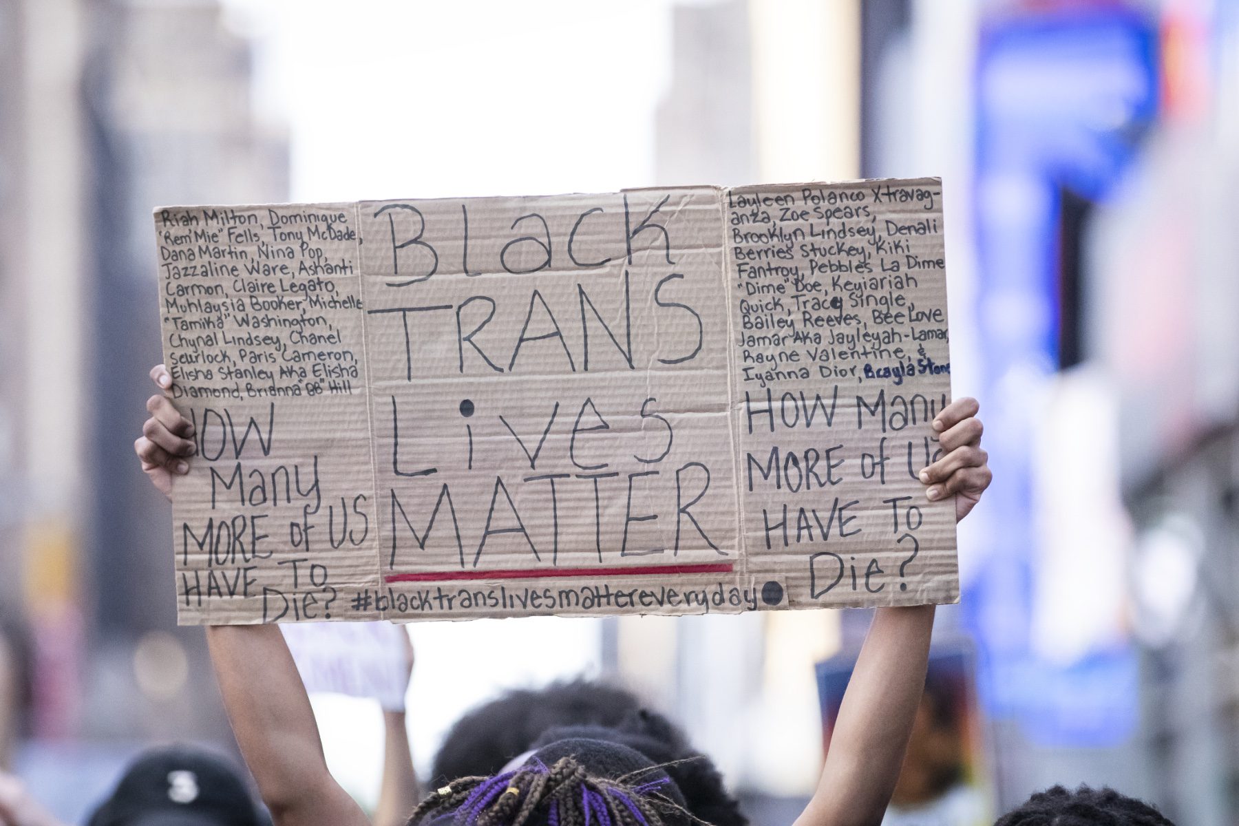 A protester holds a sign that reads, "Black Trans Lives Matter" with the names of women that have died at the hands of police.