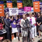 Group gathered around a woman protesting abortion measures.