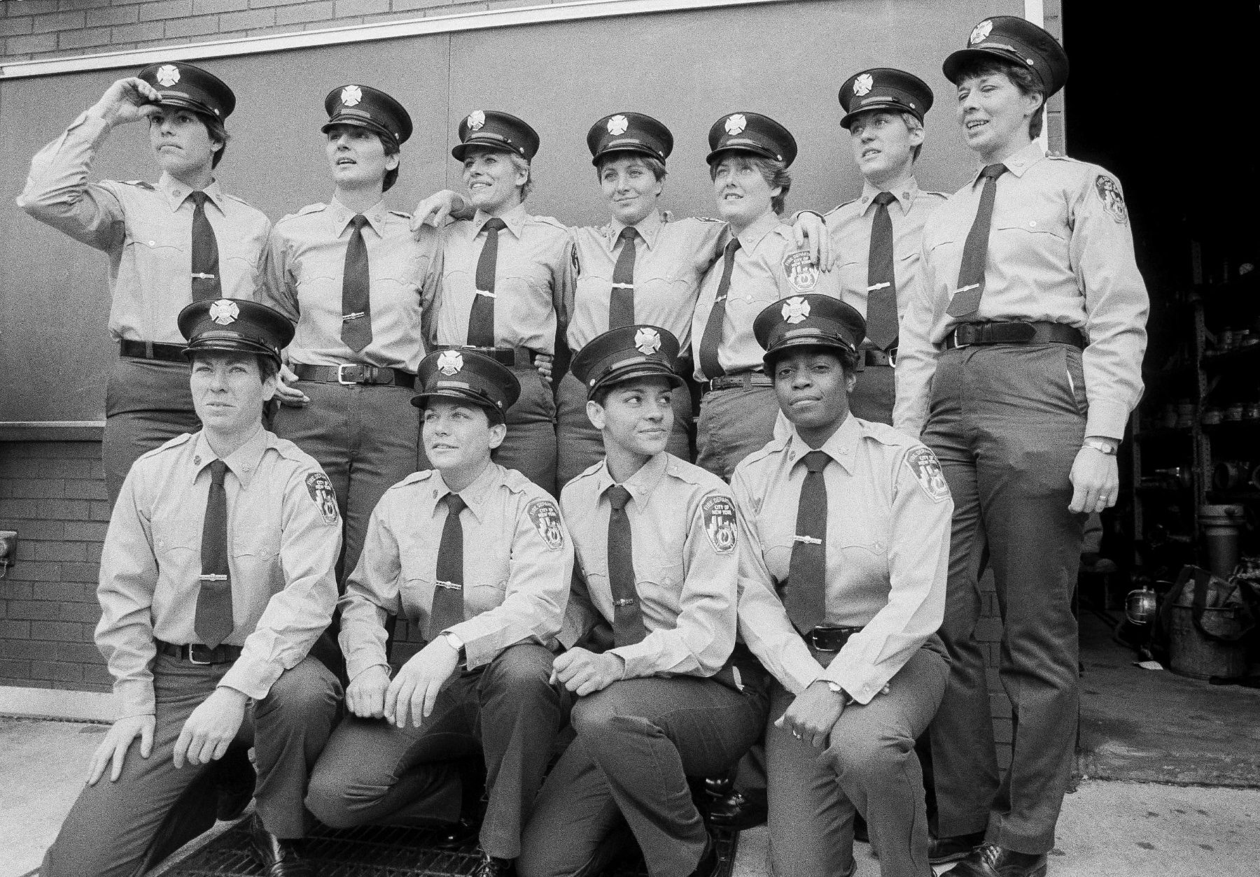 A group of woman firefighters pose in a black and white photo.