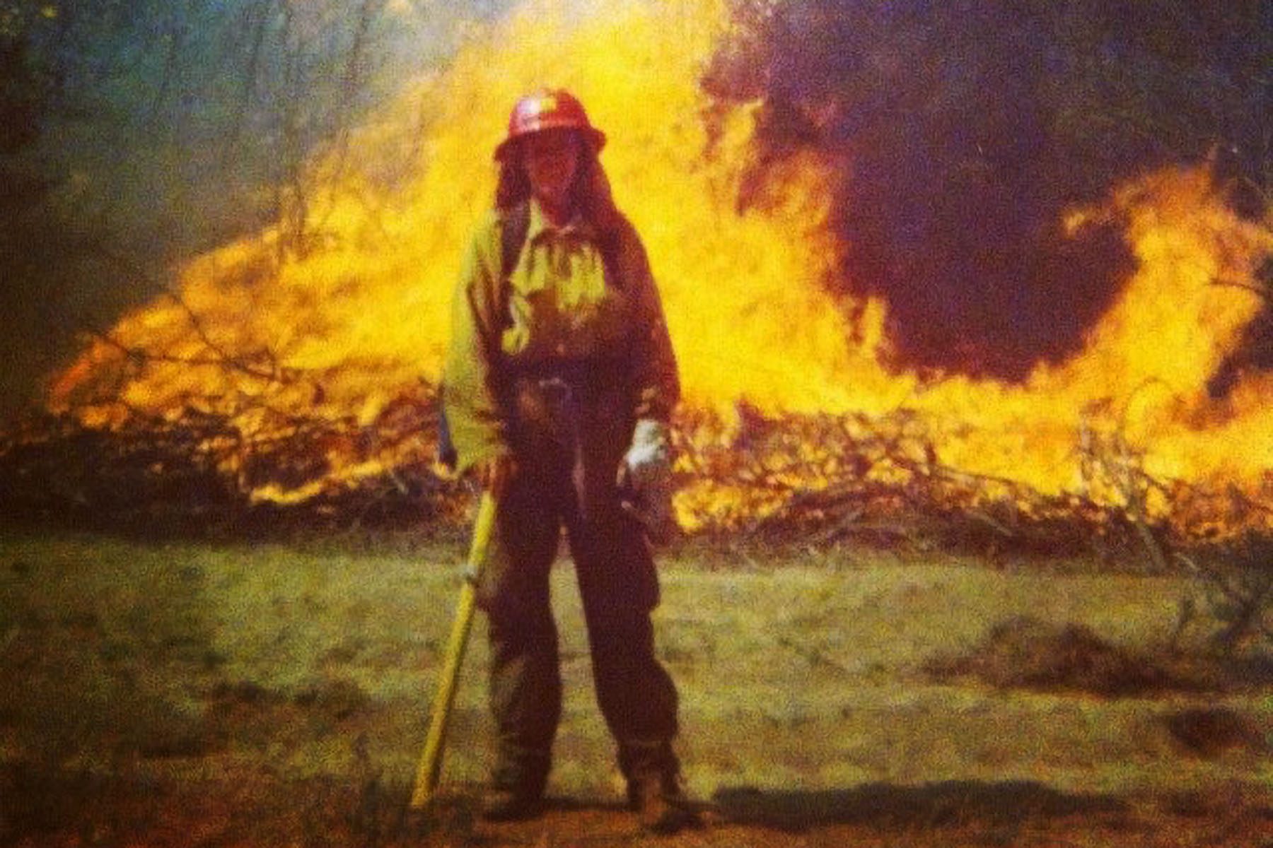 Stacy Selby poses for a photo in front of a fire.