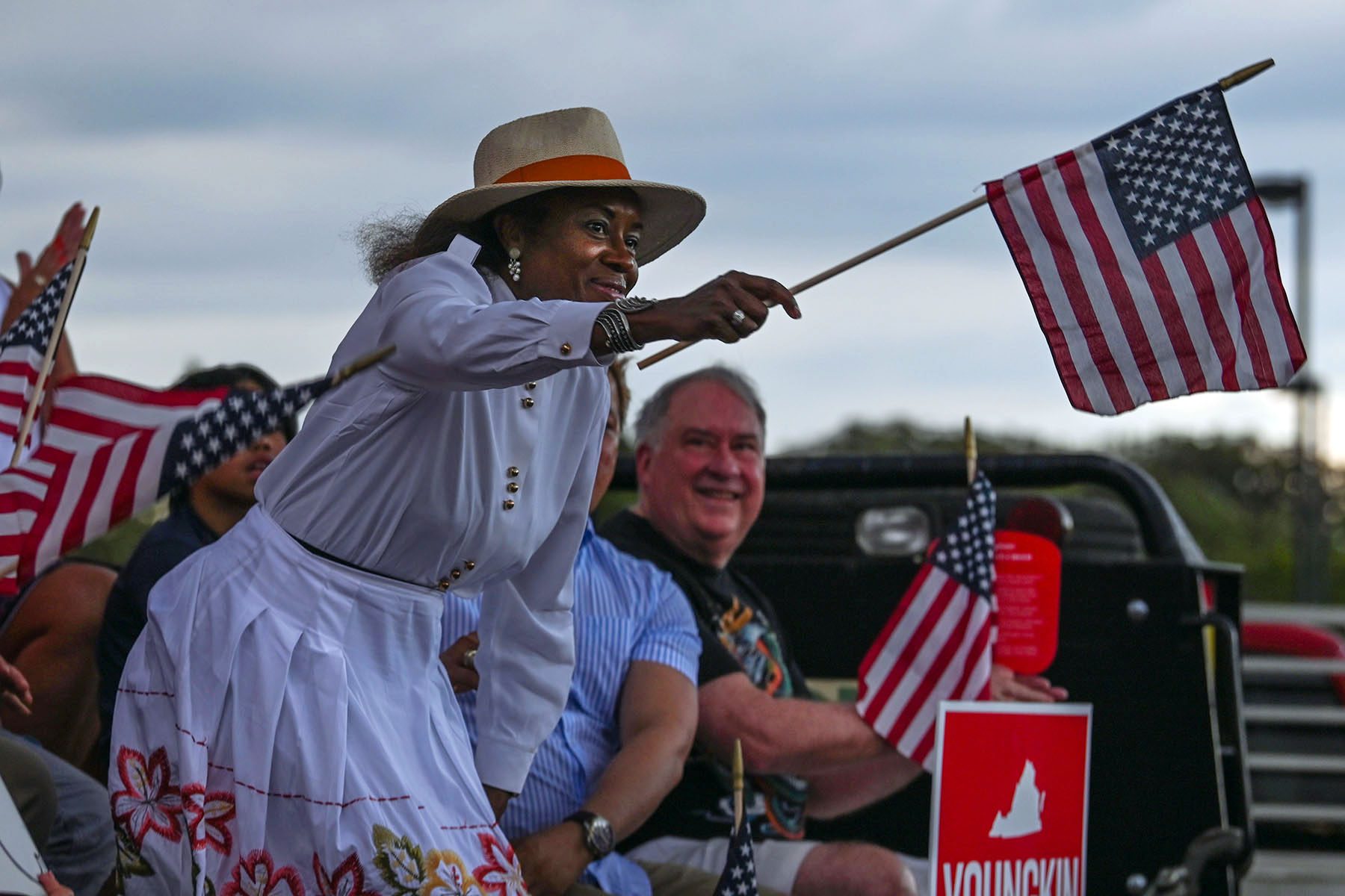 Winsome Sears smiles and waves an American flag at an event.