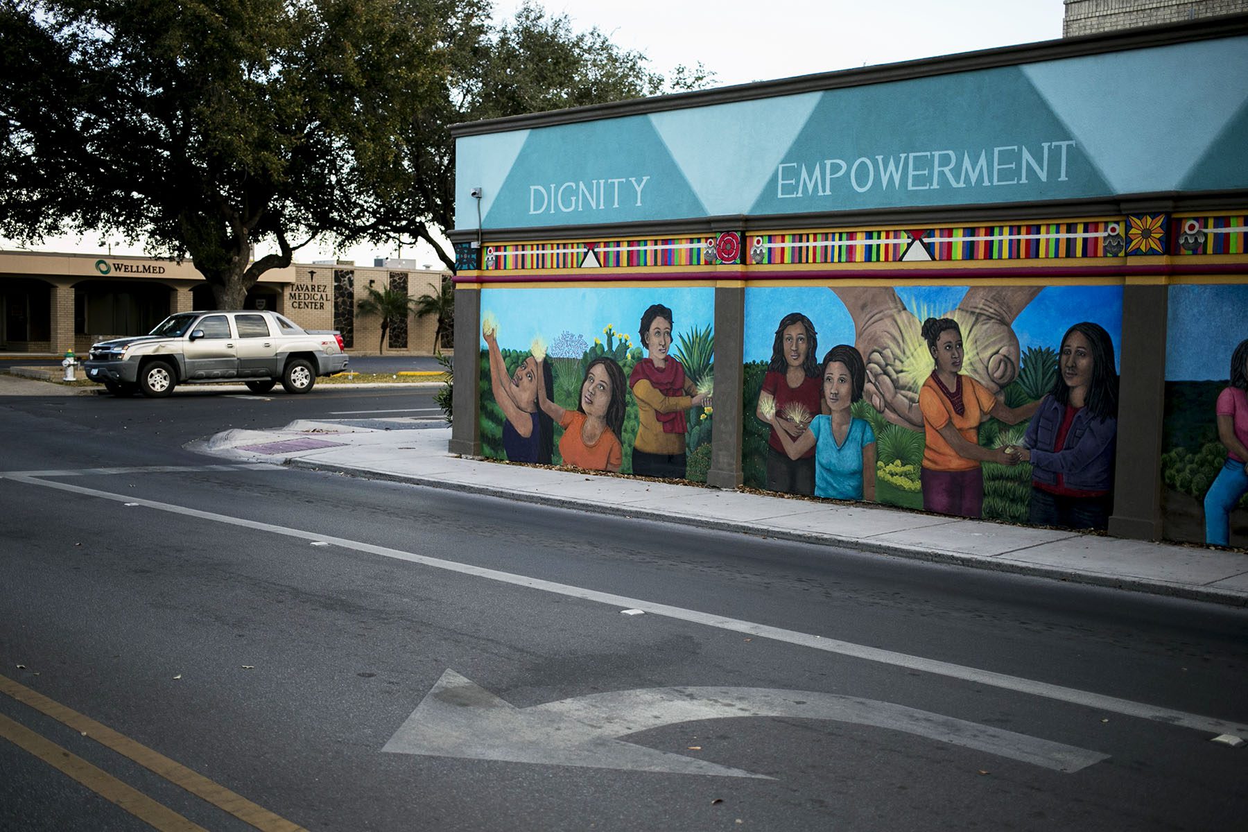 A mural painted on the side of the clinic has the words 'dignity,' 'empowerment,' 'compassion,' and 'justice' accompanying a painted scene where women hold hands and comfort each other.