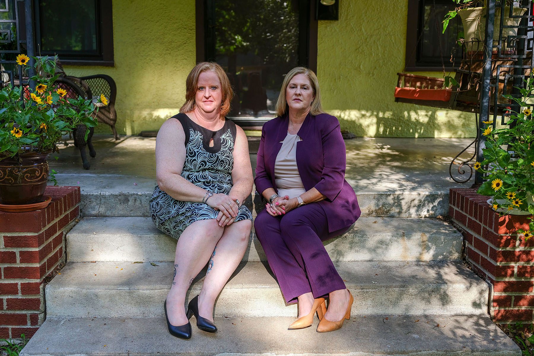 Christie and Julie Burkart pose for a portrait sitting on the stairs of Julie's front porch.