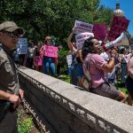 A capitol policeman surveils demonstrators.