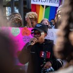 A person speaks in the midst of a walkout as protesters hold signs.