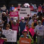 A crowd of abortion rights activists carry signs while demonstrating.