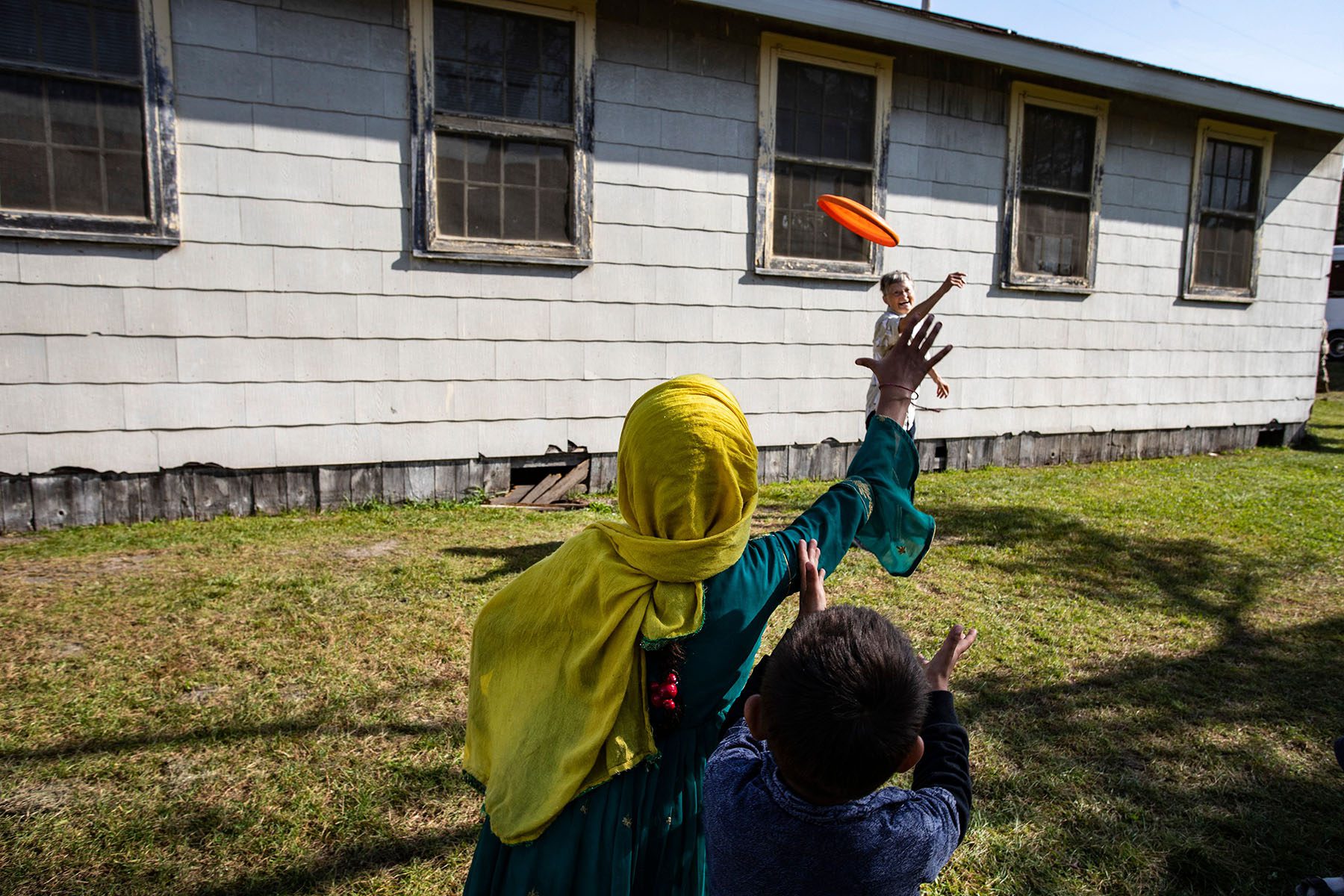 A volunteer plays frisbee with Afghan refugees children.