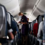 Flight attendants hand out refreshments to a packed Delta Airlines flight.