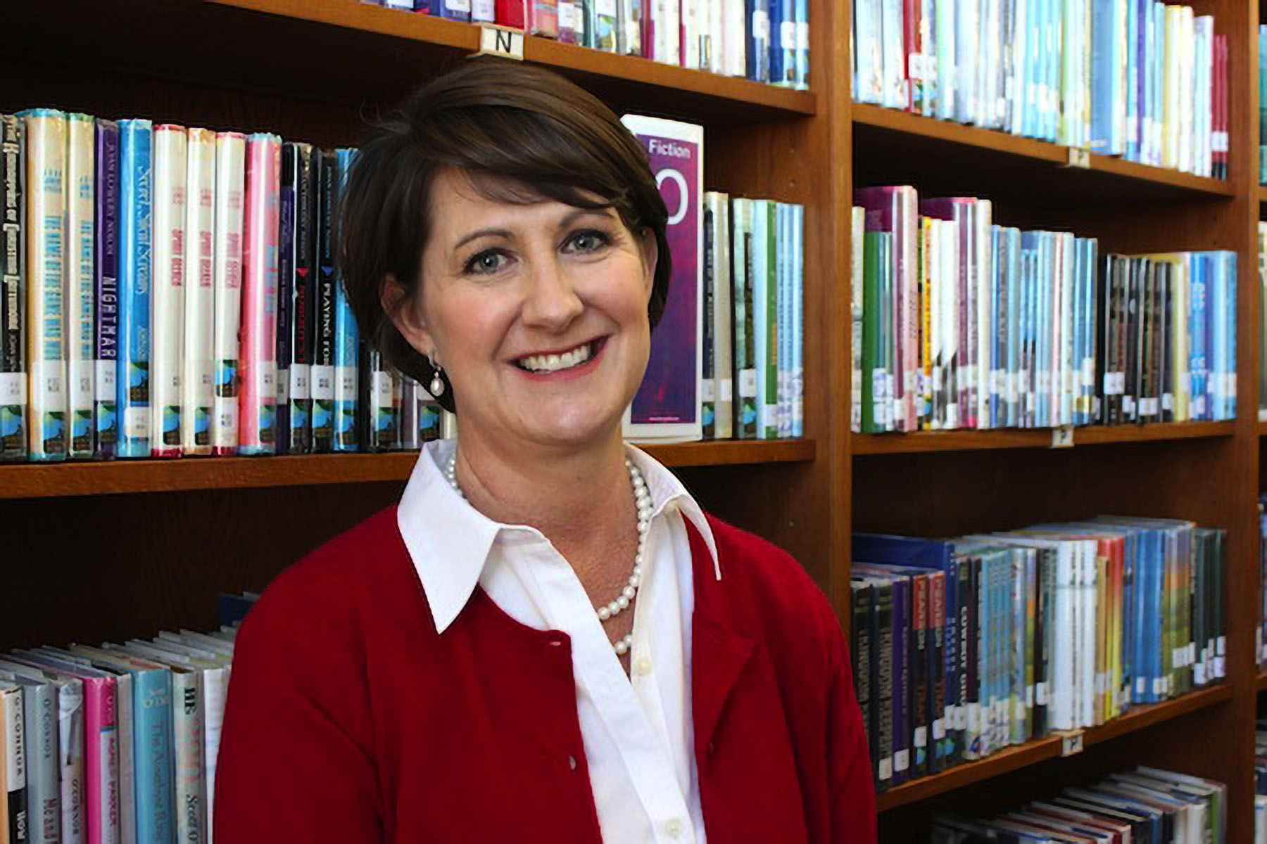 Jill Bellomy smiles in a school libraby.
