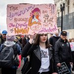 A woman holds up a sign that reads 