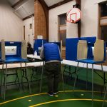 People fill out their ballots at a school.