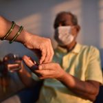 A woman hands a senior man his medicine.