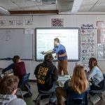 A teacher points at the board during a statistics class.