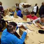 Workers sit around a table while taking care of shipping orders.