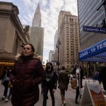 Pedestrians pass a covid-19 testing booth on a busy New York City street.