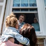 Francis Piscatella says hello to family members through a window.