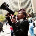 A demonstrator shouts slogans through a megaphone as she marches.