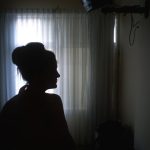 Silhouette of a woman in a room near the window.