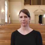 Kalie Hargrove stands in front of pews in a church